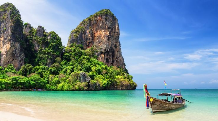 An image showing part of Thailand's coastline with a sailboat.